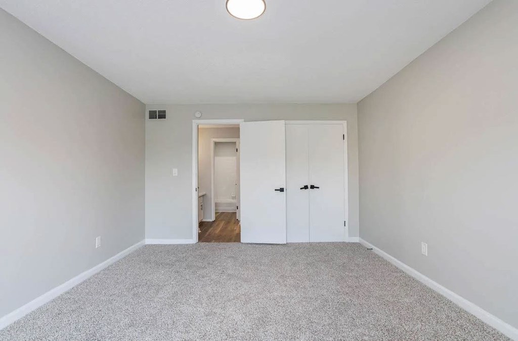 A room with a carpeted floor and two white doors. A room with a carpeted floor and two white doors at The Onyx Hoover Apartments, Alabama