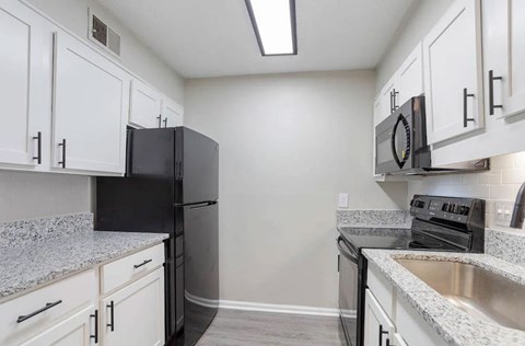 A kitchen with a black refrigerator and stainless steel appliances at The Onyx Hoover Apartments, Hoover