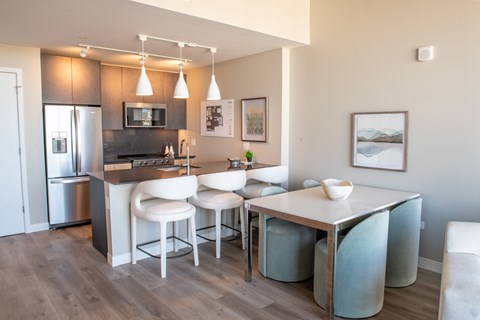 A modern kitchen with a bar stool and a fridge.
