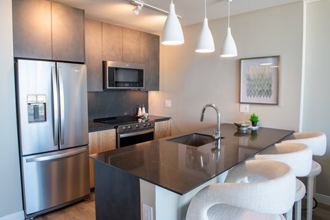 A modern kitchen with a black countertop and stainless steel appliances.