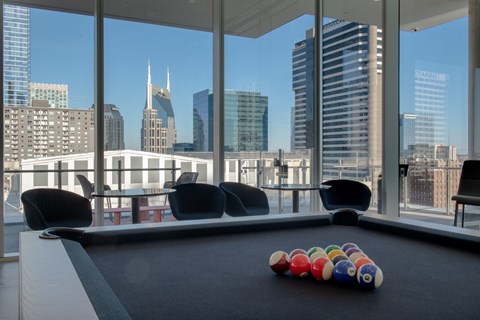 A pool table with a set of balls on it in front of a city skyline.