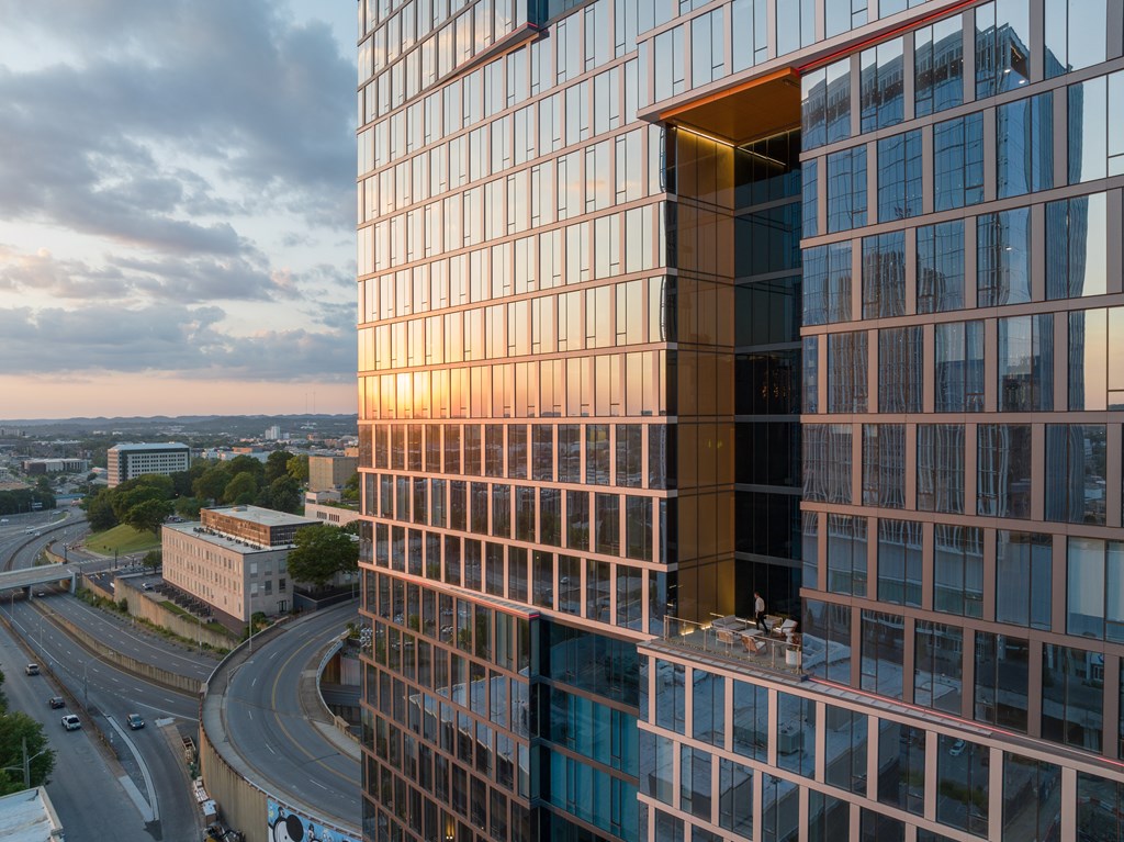 A modern glass building with a curved corner reflecting the sky.