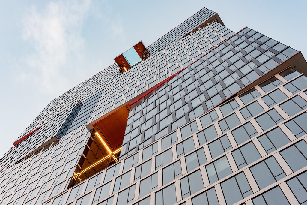 A modern building with a glass facade and a red stripe running along the top.