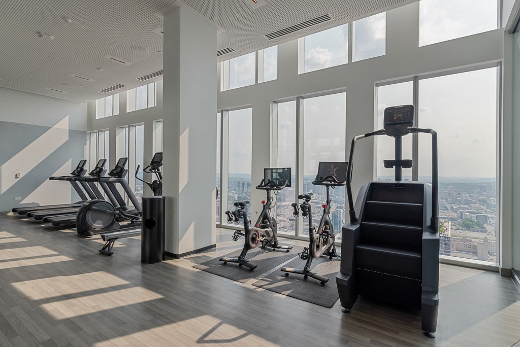 a gym with a row of exercise machines and a view of the city