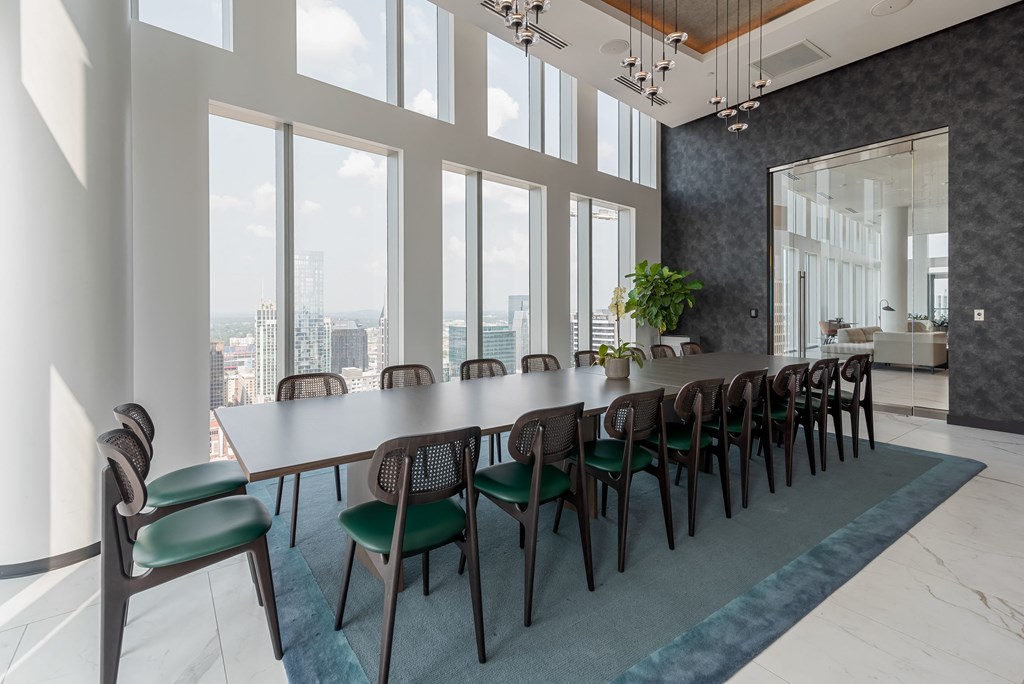 a long table with chairs in a room with large windows