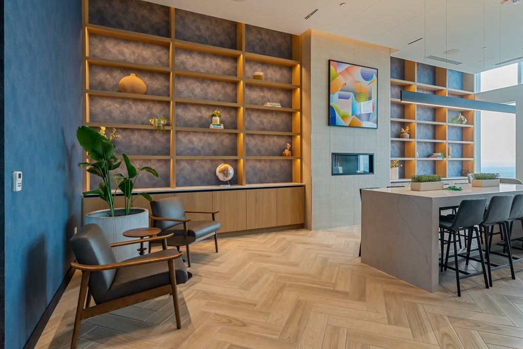 a lobby with chairs and a table and a wall with shelves