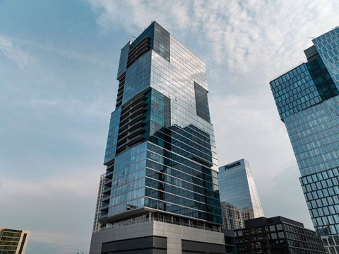 A modern skyscraper with glass windows stands tall among other buildings.