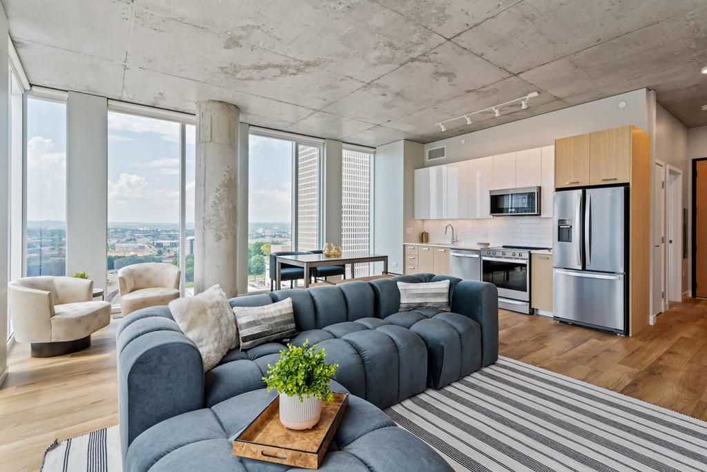 a living room with a blue couch and a kitchen with a large window