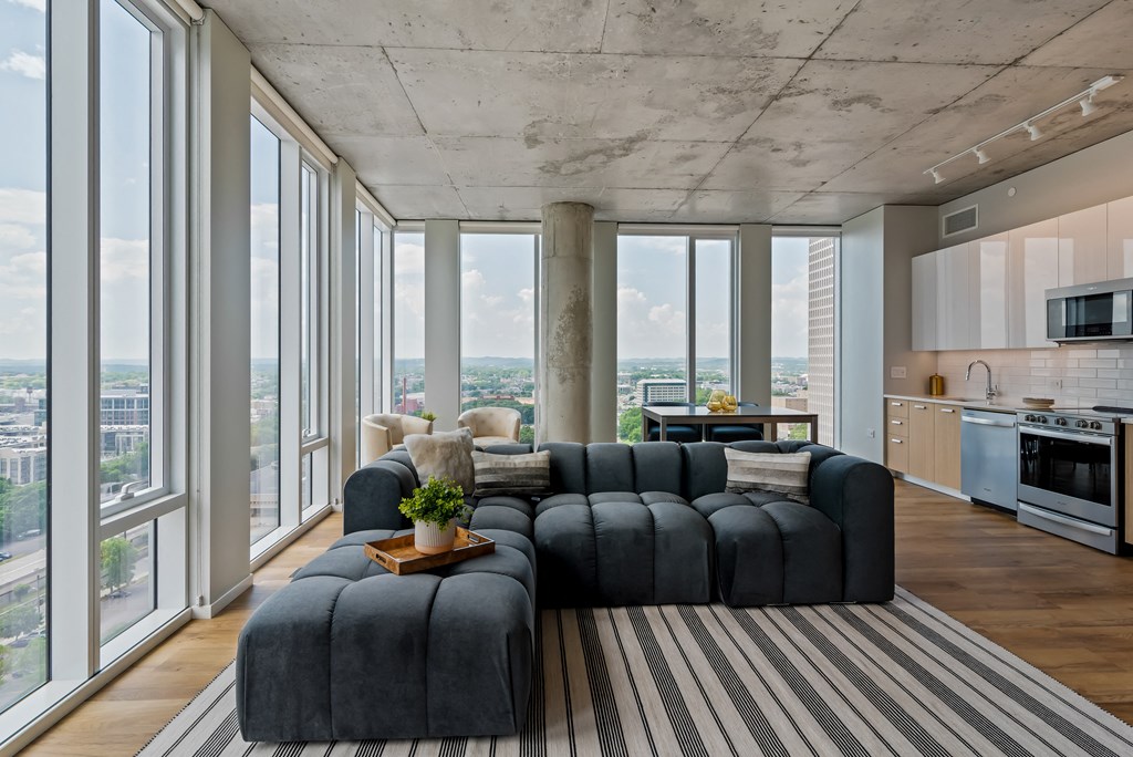a living room with a gray couch and a rug and floor to ceiling windows