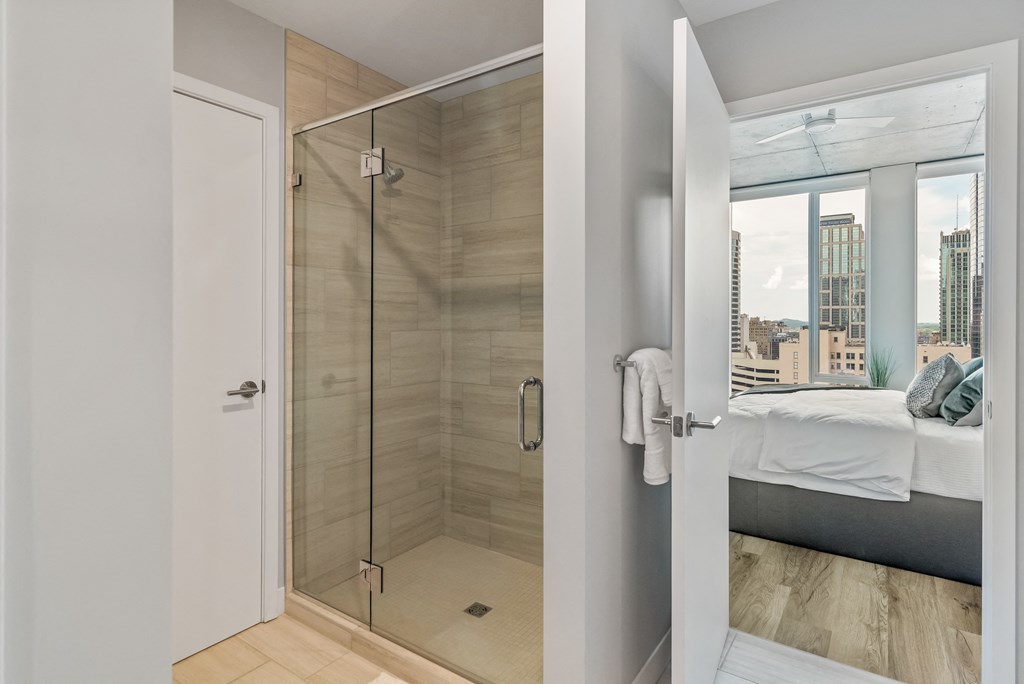 a bathroom with a shower and a bed in a room