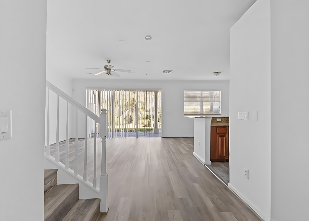 an empty living room with a staircase and a kitchen