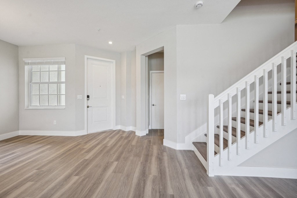 an empty living room with a staircase and a white door
