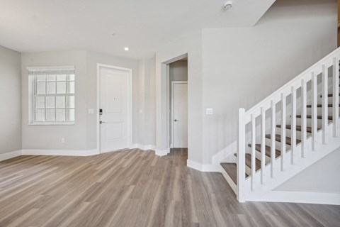 an empty living room with a staircase and a white door