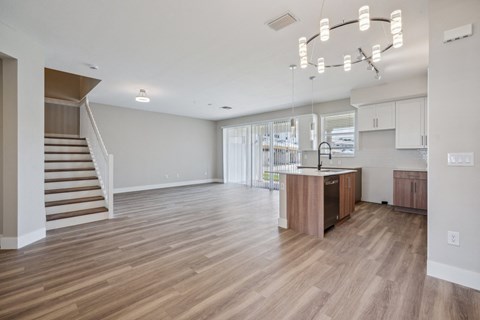a living room and kitchen with a staircase and a kitchen island