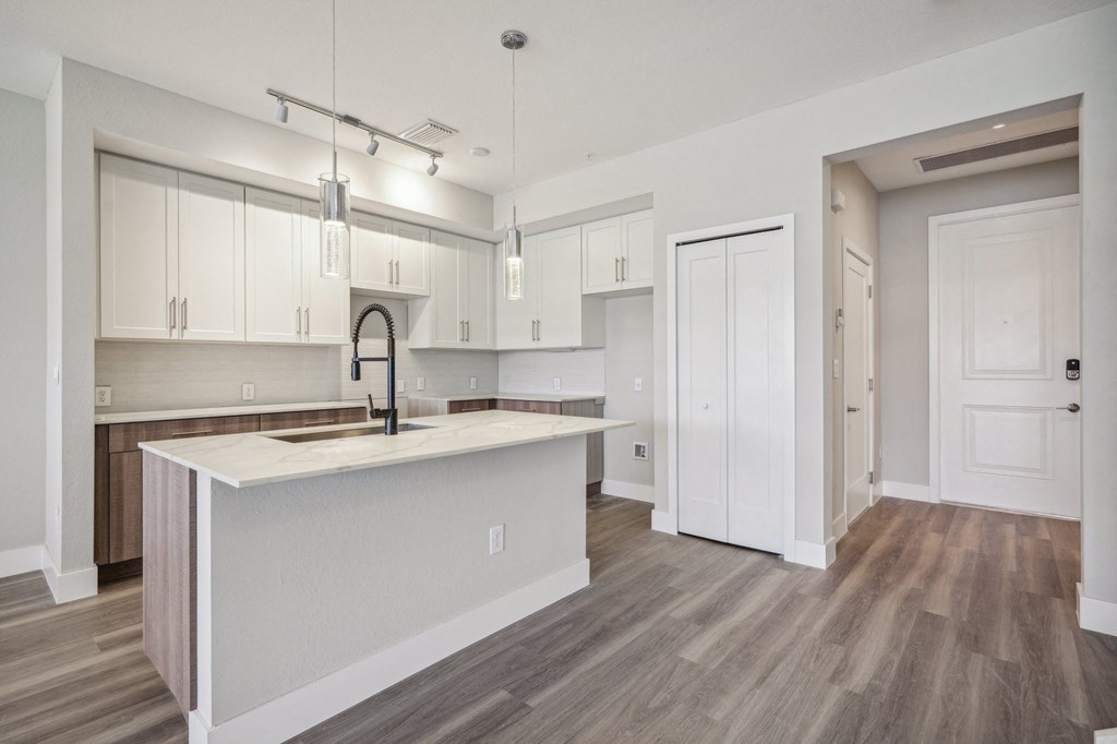 an open kitchen and living room with white cabinets and a white counter top