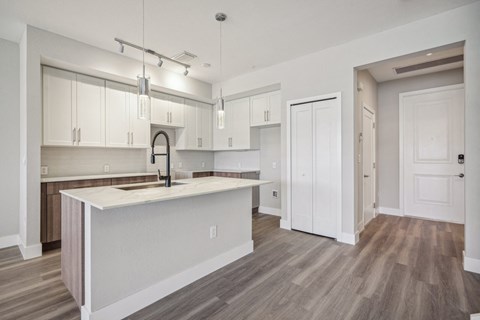 an open kitchen and living room with white cabinets and a white counter top
