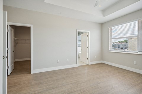 the living room of an apartment with a large window and wooden floors