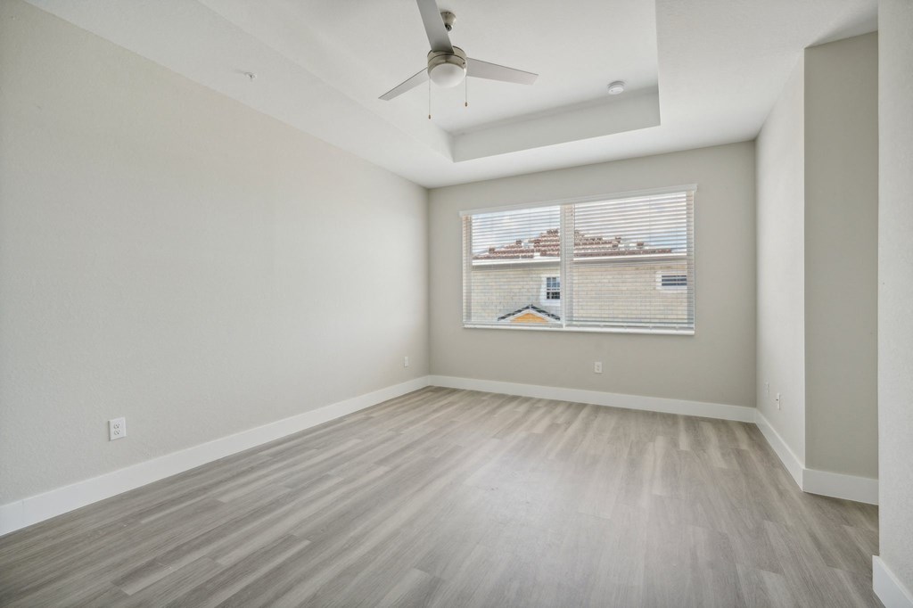 an empty living room with a window and a ceiling fan