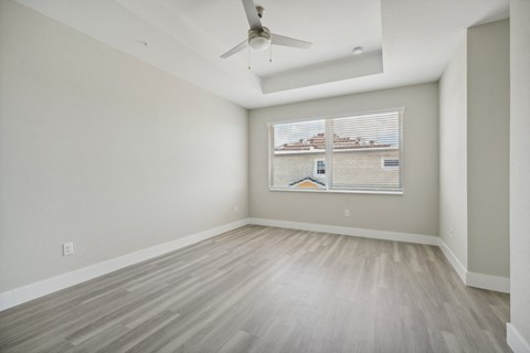 an empty living room with a window and a ceiling fan