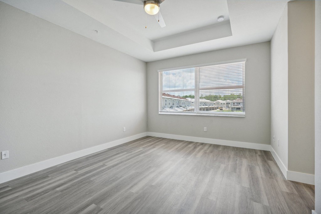 the living room of an apartment with wood floors and a large window