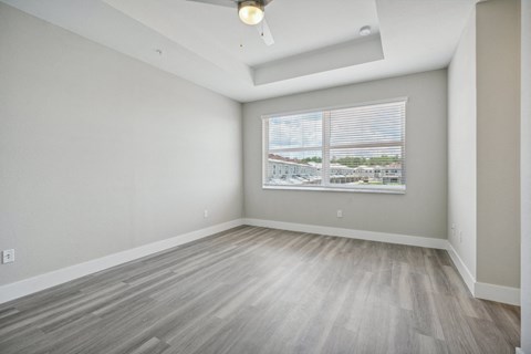 the living room of an apartment with wood floors and a large window