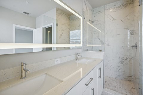 the ensuite bathroom has two sinks and a large mirror