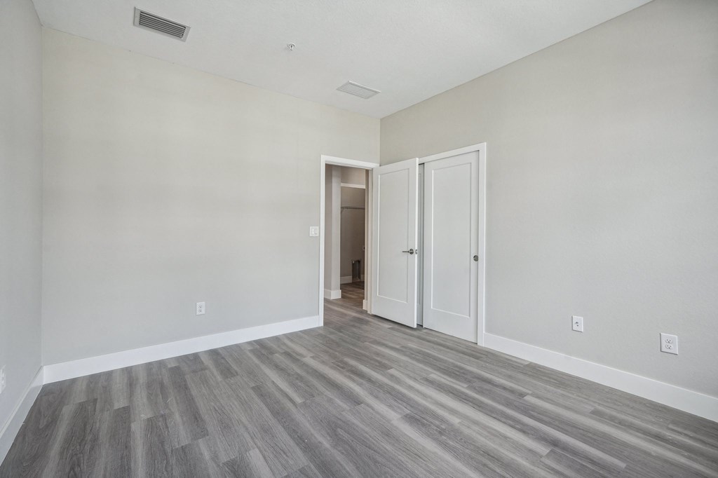 an empty bedroom with white walls and wood flooring