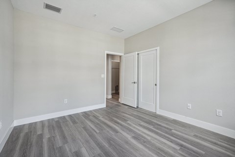 an empty bedroom with white walls and wood flooring