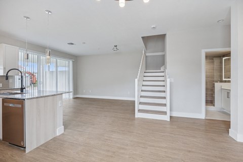an open kitchen and living room with a staircase to a loft
