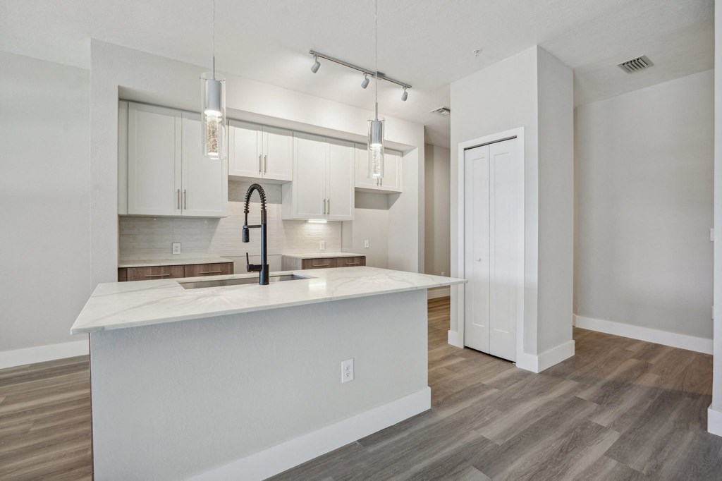 a kitchen with white cabinets and a large island with a black faucet