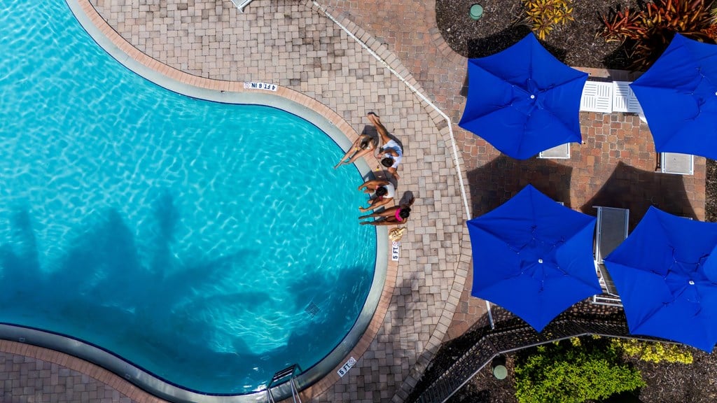 A swimming pool with blue umbrellas and people enjoying the water.