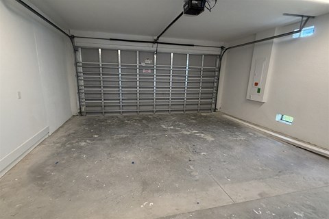 A garage with a closed metal gate and a concrete floor.