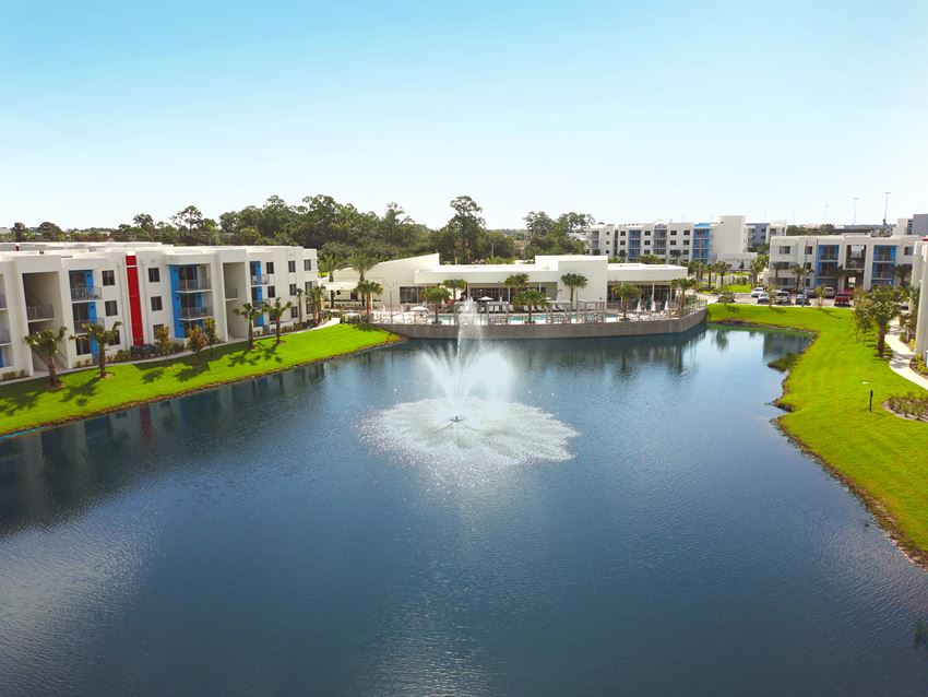 Lake with fountain surrounded by Icon One Daytona apartments on the left and right and clubhouse and pool centered Lake with fountain surrounded by Icon One Daytona apartments on the left and right and clubhouse and pool centered at Icon One Daytona, Daytona Beach, FL - Photo Gallery