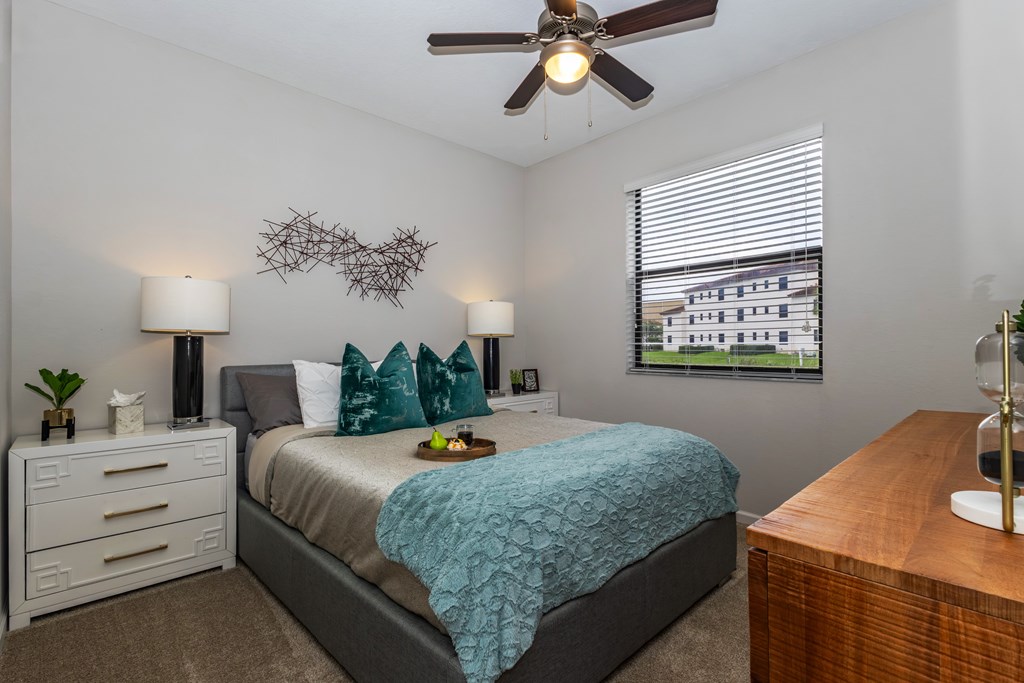 A bedroom with a bed, nightstand, and window.