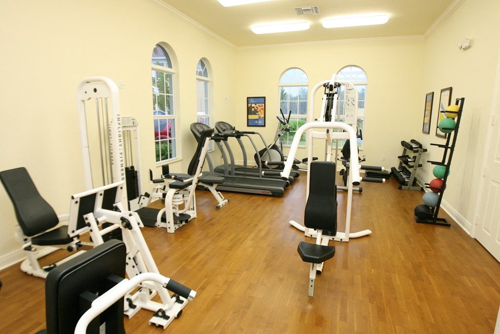 a gym with cardio equipment and weights on a wooden floor
