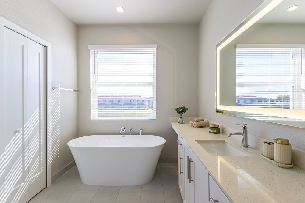 A white bathroom with a tub, sink, and a window.