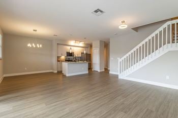 A spacious living room with a staircase on the right side.