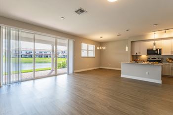 A spacious living room with a kitchenette and sliding glass doors leading to a patio.