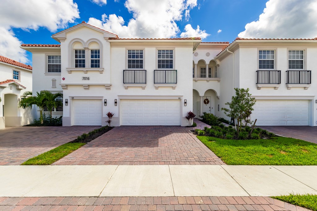 A white house with a red roof and a garage door.