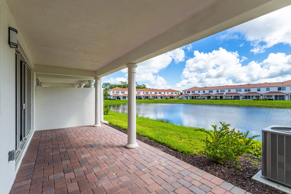 A patio with a brick floor and a white wall.