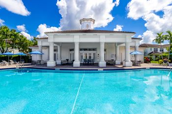 A white building with a pool in front of it.
