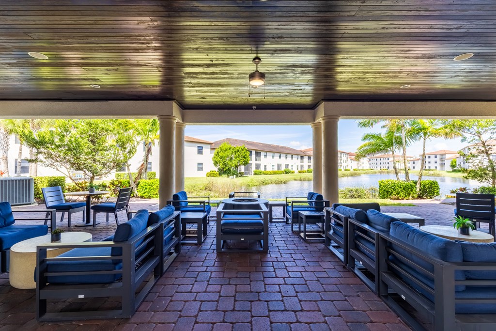 A patio with blue chairs and tables overlooking a body of water.