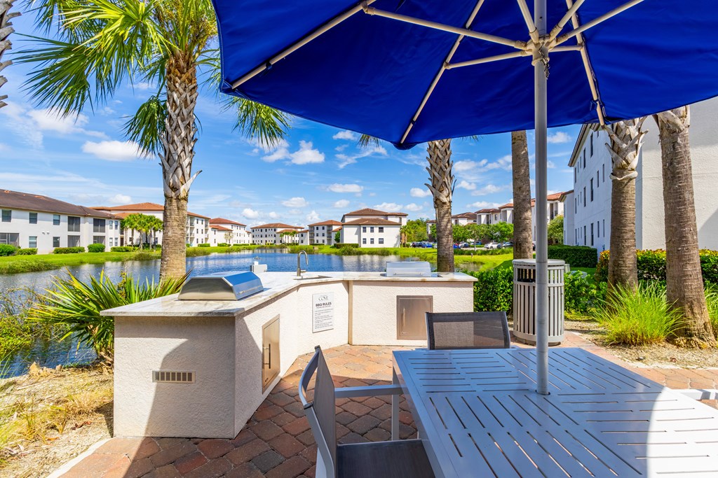 A blue umbrella is over a table and chairs.