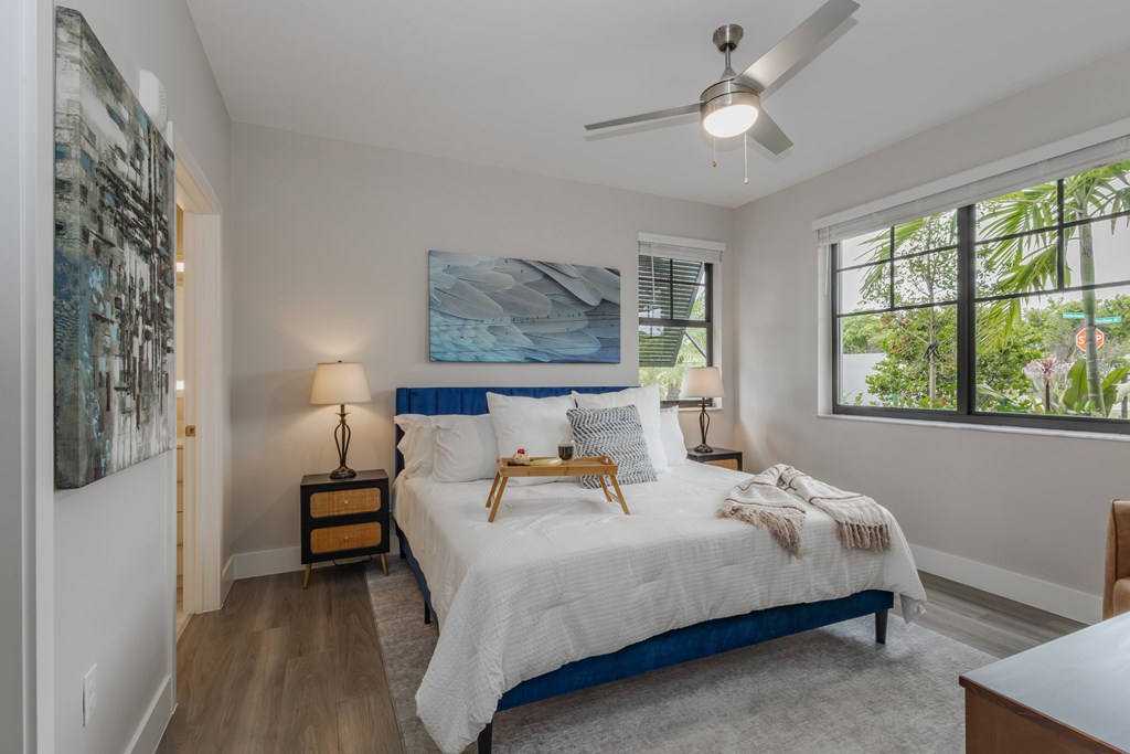 A bedroom with a bed, nightstand, and a painting on the wall.