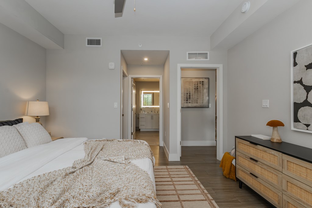 A bedroom with a bed, dresser, and a painting on the wall.