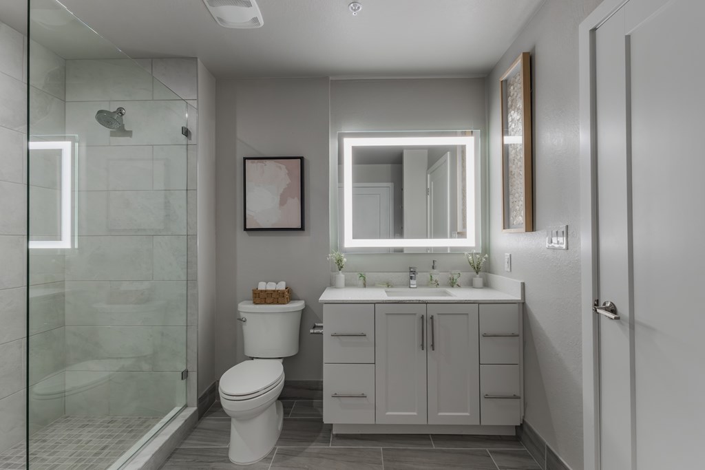 A white toilet sits in a modern bathroom with a glass shower.