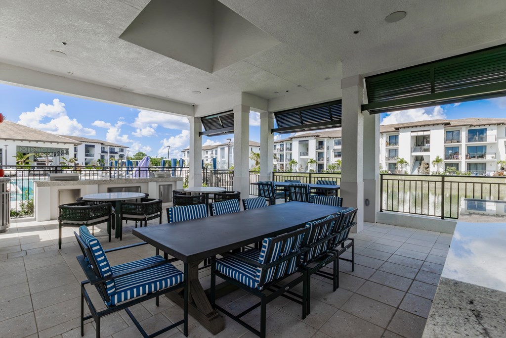 A patio with a table and chairs overlooking a pool.