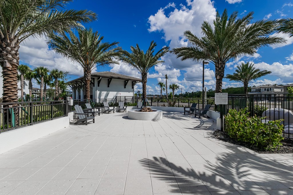 A sunny day at the park with palm trees and a white building in the background.