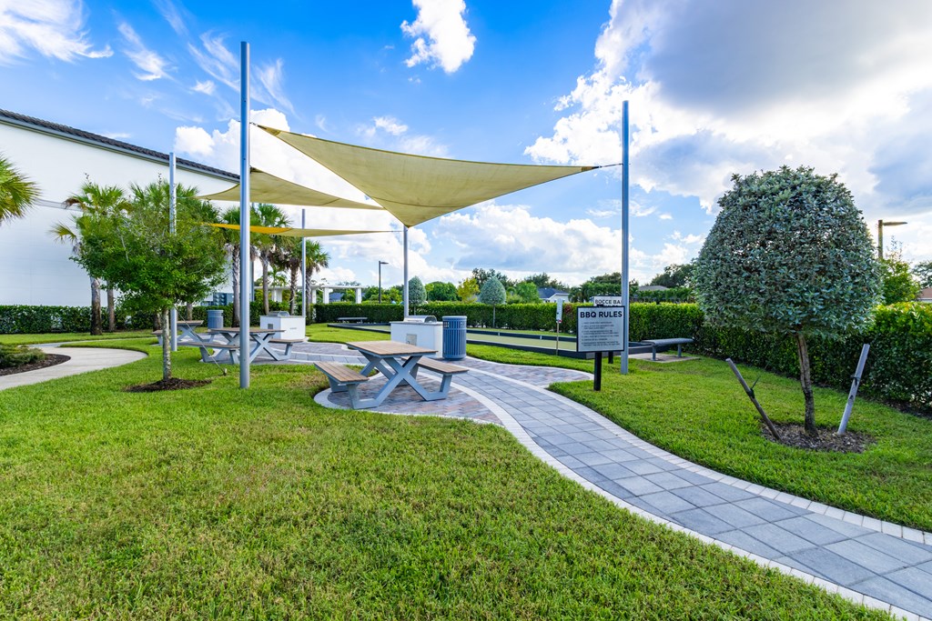 A park with a walkway, trees, and a white canopy.