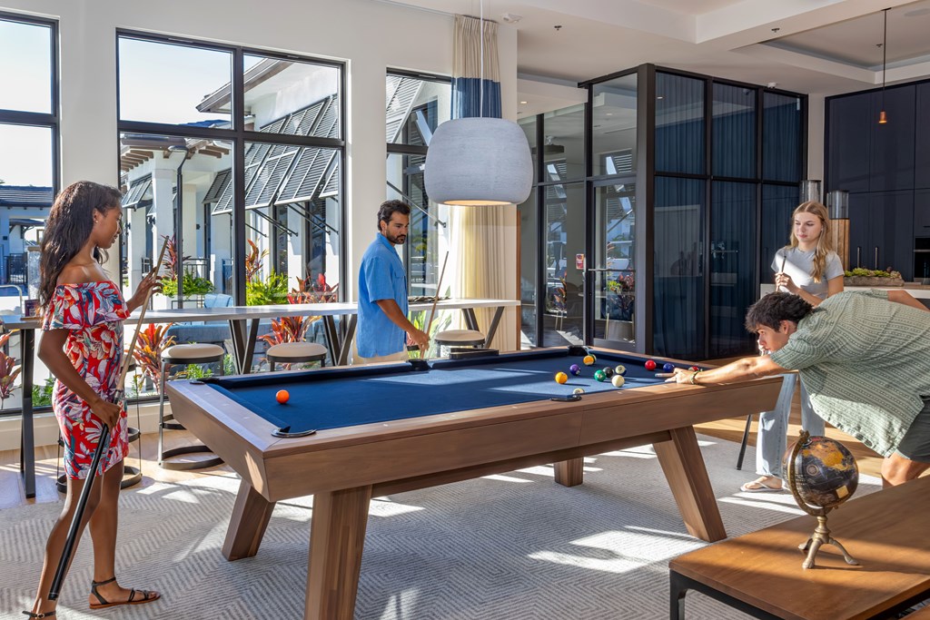 A group of people playing pool in a brightly lit room.